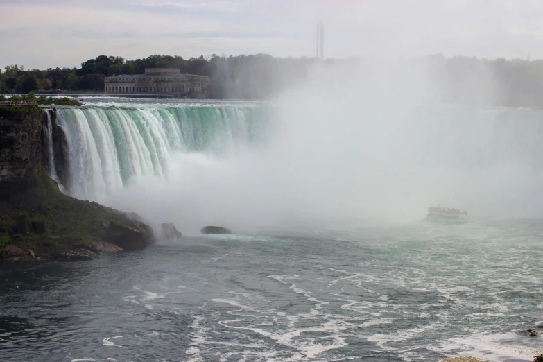 a boat is floating in the water by a waterfall