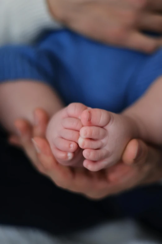 baby laying on mother's chest with hands holding him