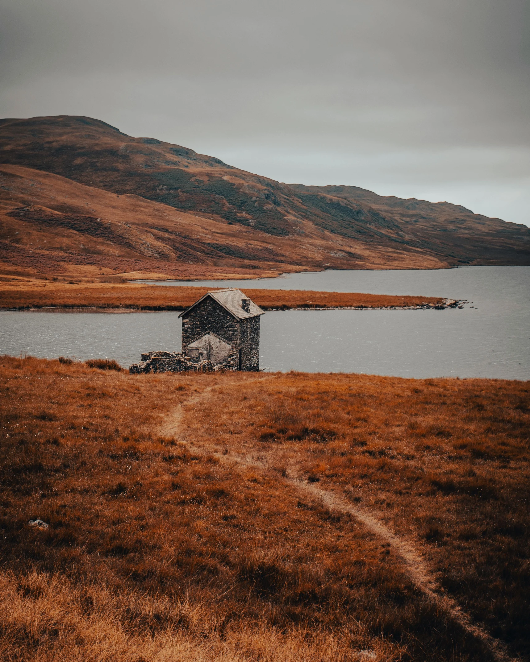 a house is built in a dry and grassy area by a body of water