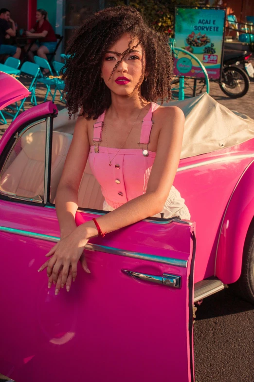 a woman leaning on the front door of a pink vintage car