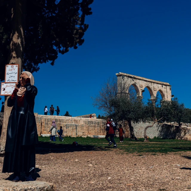 a woman wearing a black robe and standing in front of an old stone building