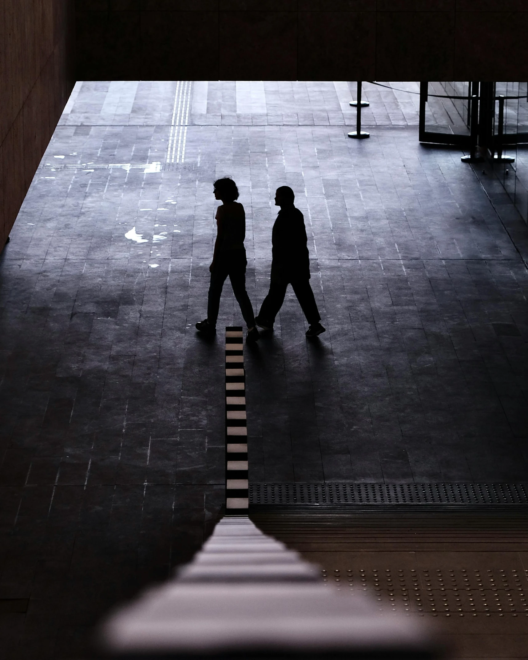 two people walking down a large, dark and dirty floor