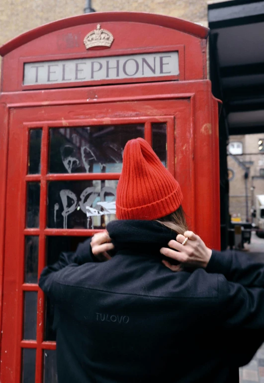 a man in a red cap is leaning on the phone booth