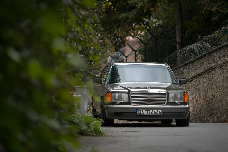 this mercedes is parked along the side of a narrow road