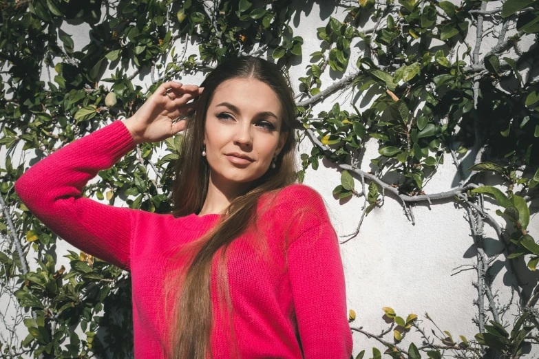 a woman poses for a picture in front of some ivy