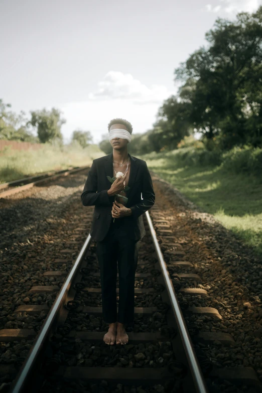 a woman wearing a blindfold on railroad tracks