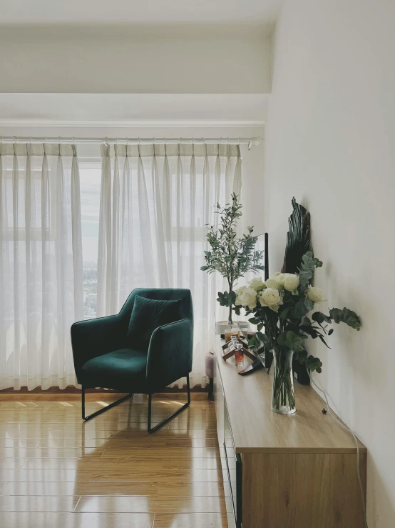 a living room has a blue chair and vase with white flowers