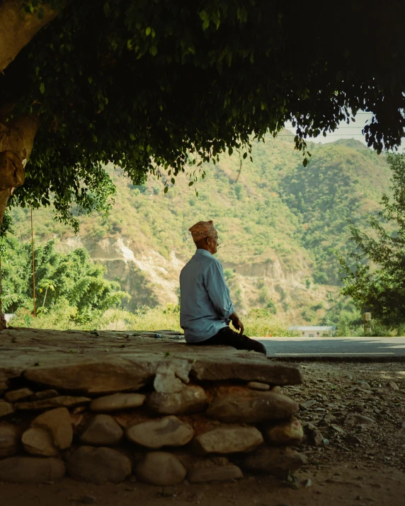 a man sitting under a tree on top of a stone floor