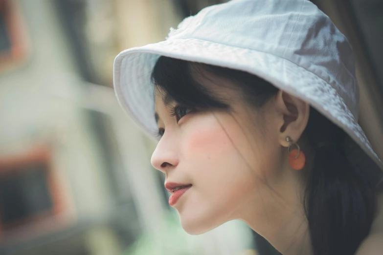 a young woman wearing a white hat looking down on the side