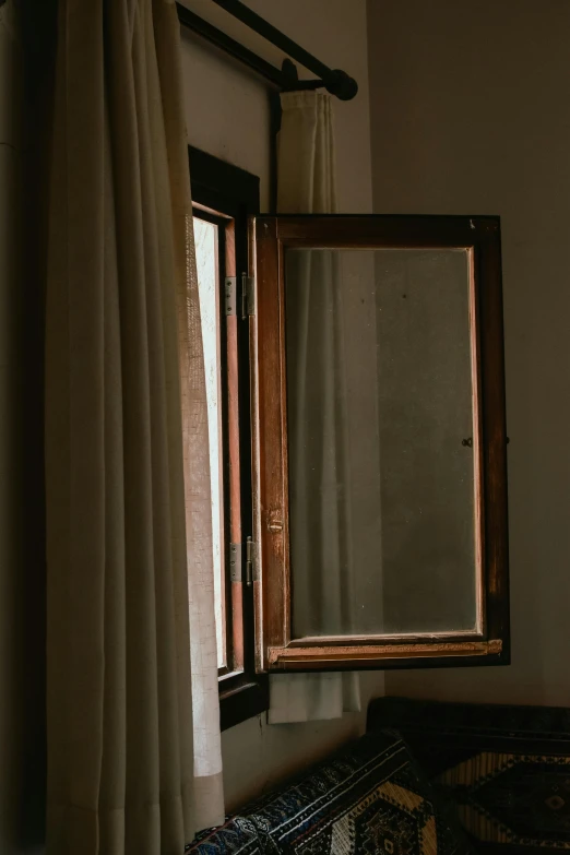 a mirror with open, wooden frames on a window