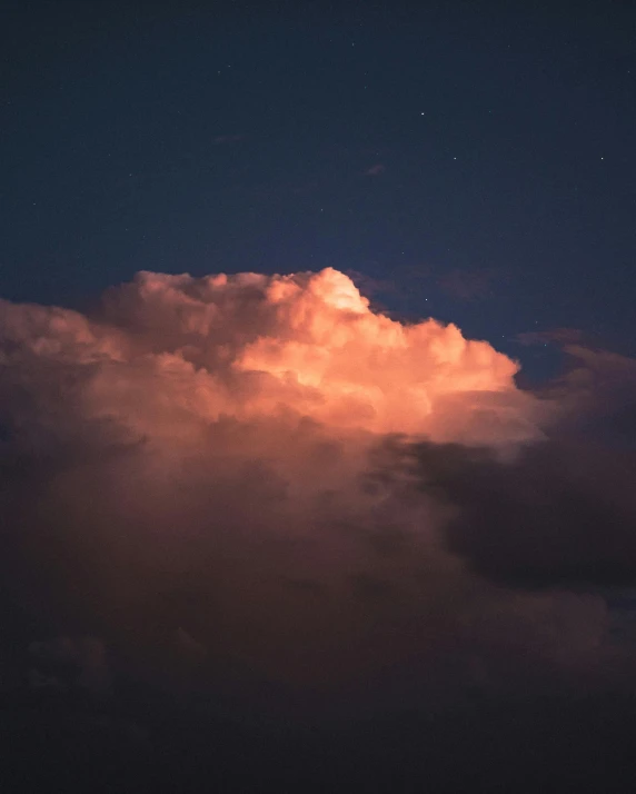 a very cloudy, dark and colorful sky with the moon visible behind it