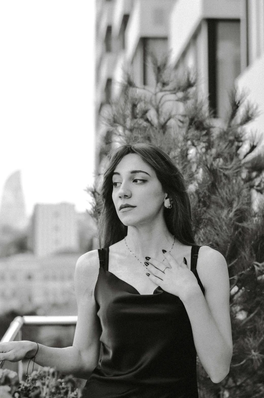 a woman in black dress leaning against tree