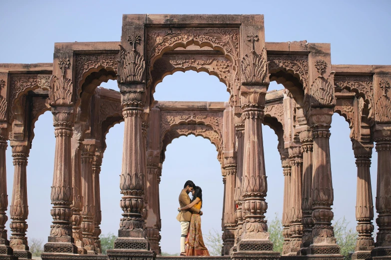 a man and woman standing under a tall arch at a palace