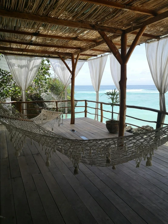 a hammock sitting on the deck near a body of water