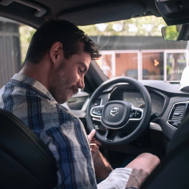 a man driving a car and looking at a cell phone