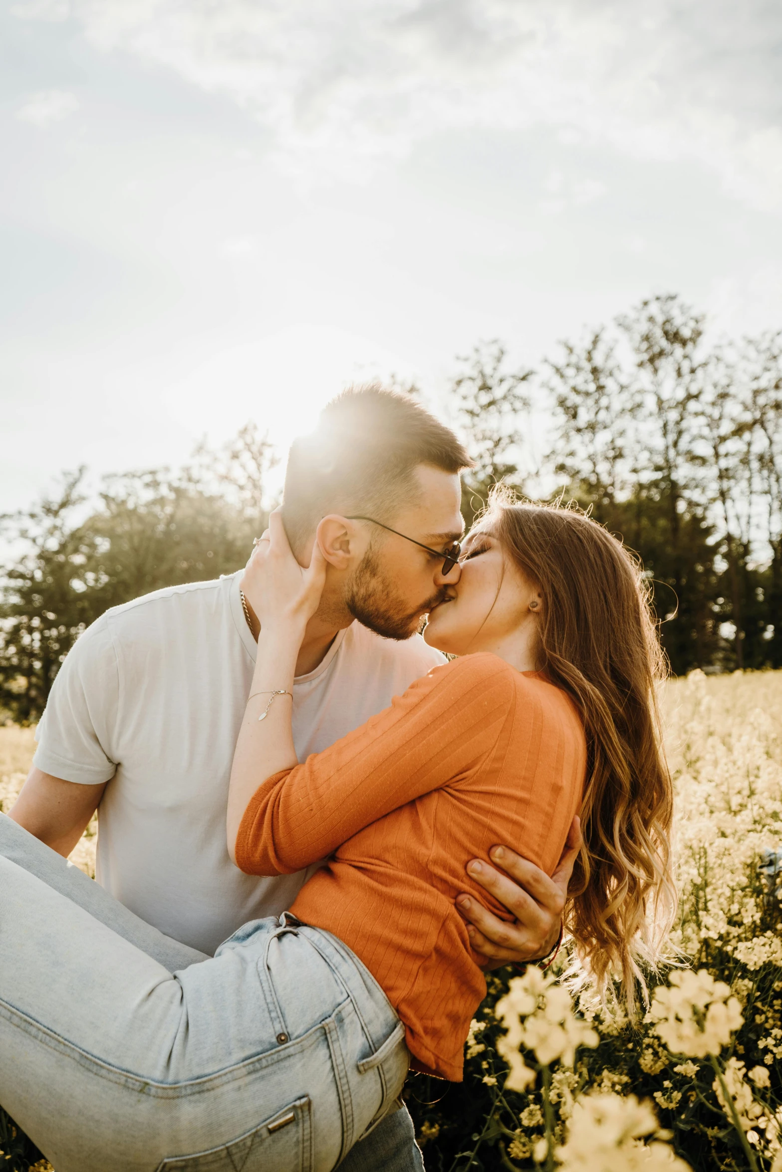 the man kisses the womans cheek as he is in a field