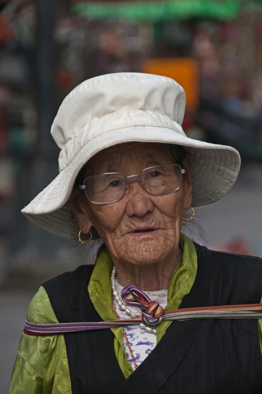 an old woman walking with a white hat on