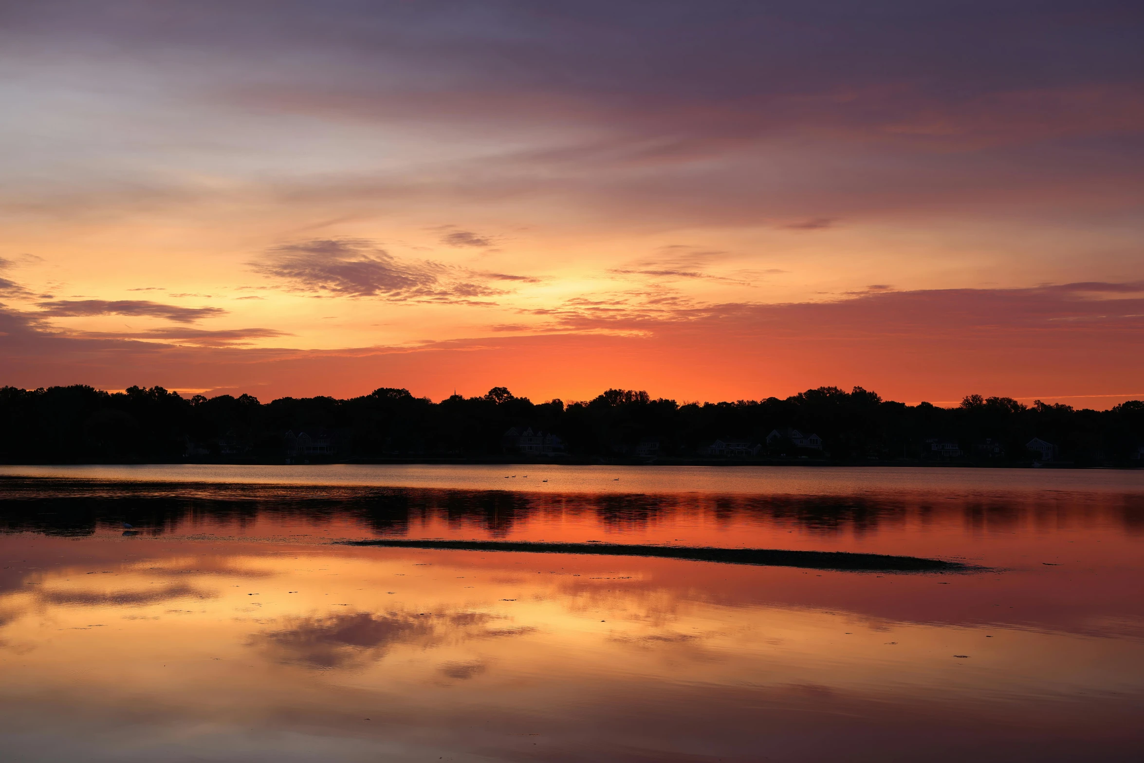 the setting sun is casting a cloud on the sky above a body of water