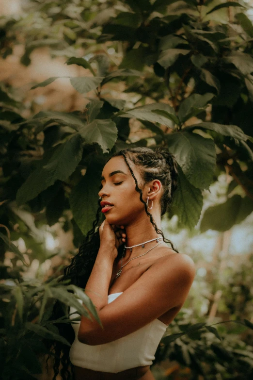 a woman in an off shoulder crop top standing under some trees