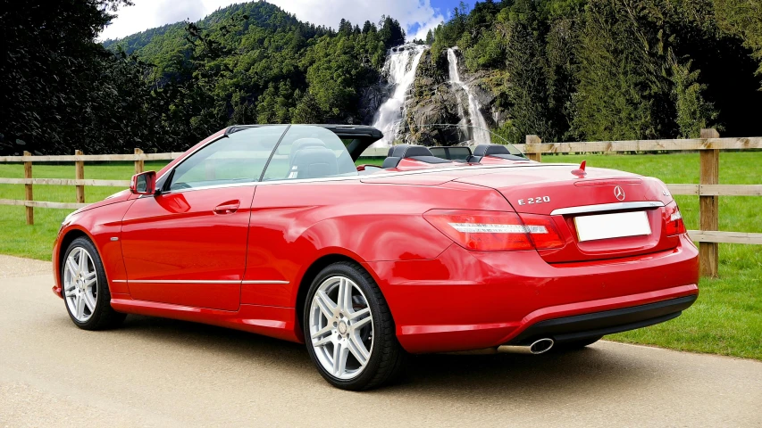 a red bmw convertible parked in front of a waterfall