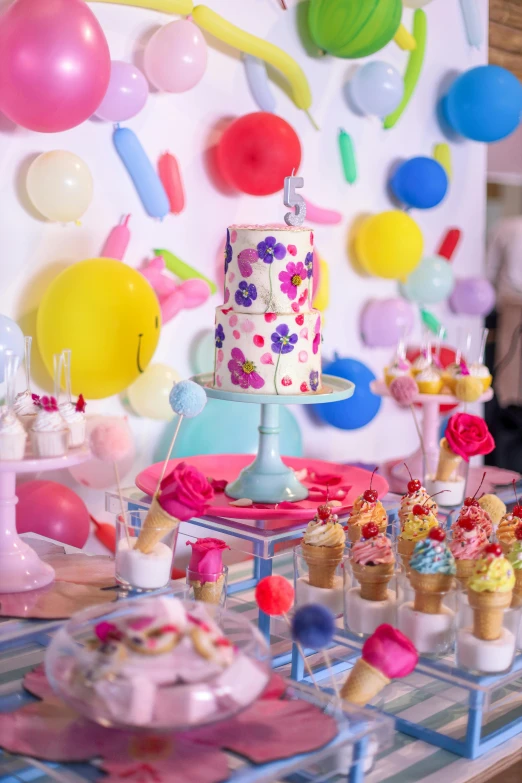 a cake is sitting on a table surrounded by balloons