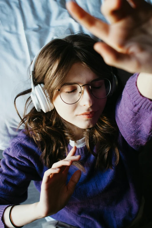 a young woman laying in bed wearing headphones