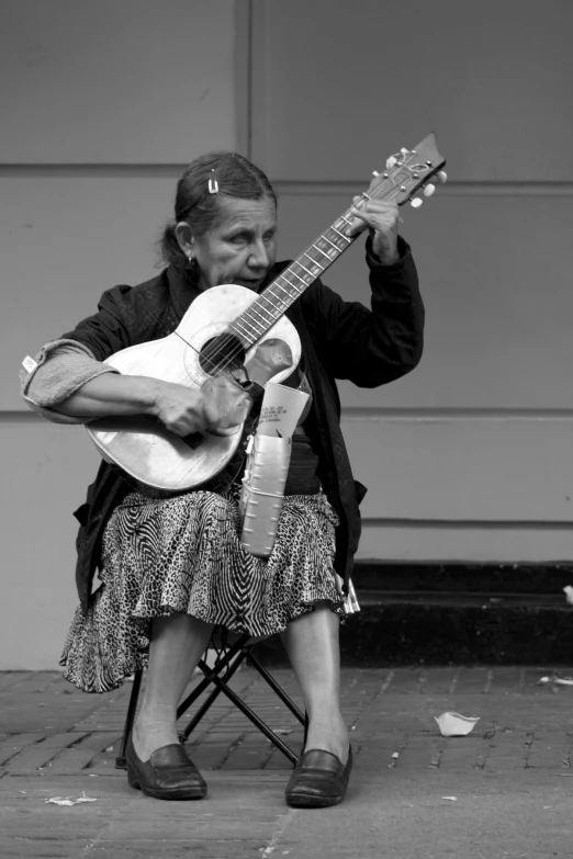 a woman is sitting on a chair playing the guitar