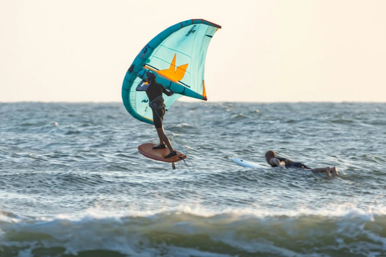 a man standing on top of a surfboard holding onto a kite