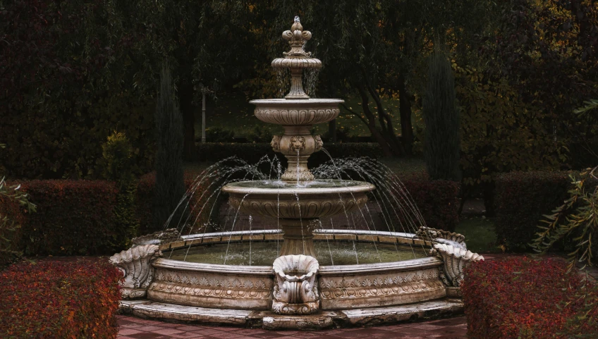 a fountain is surrounded by hedges and trees