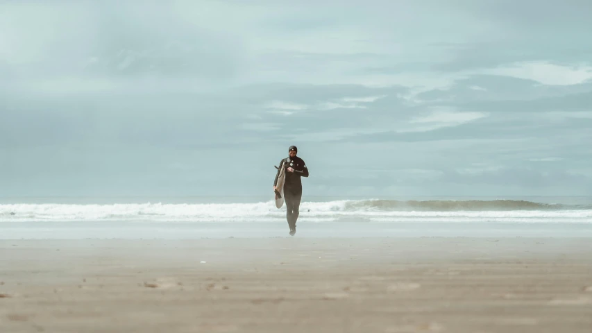 a person walking along the beach next to a surfboard