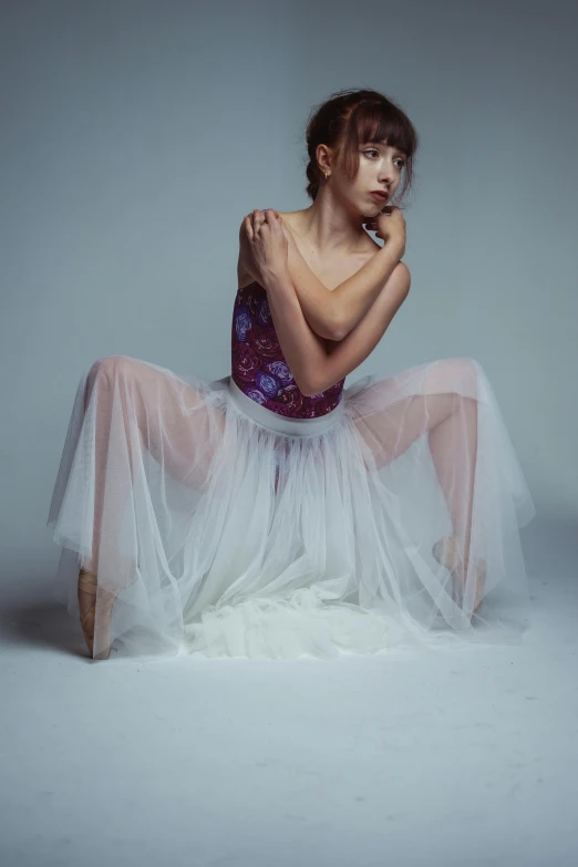 woman wearing a white and purple dress sits in a pose