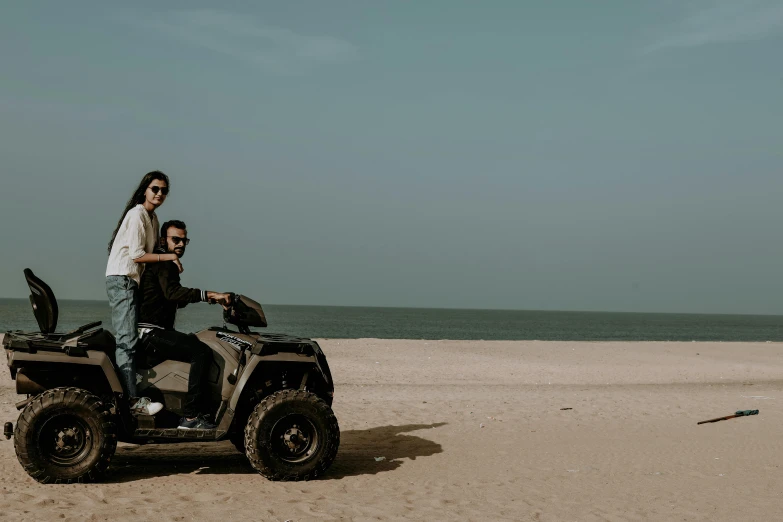 man and woman ride a quad motorcycle on the beach