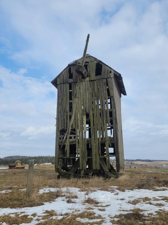 an old barn building stands in the middle of a frozen field