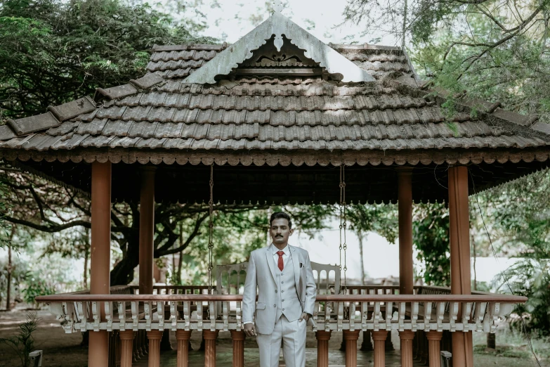 a man in white suit standing under a red roof