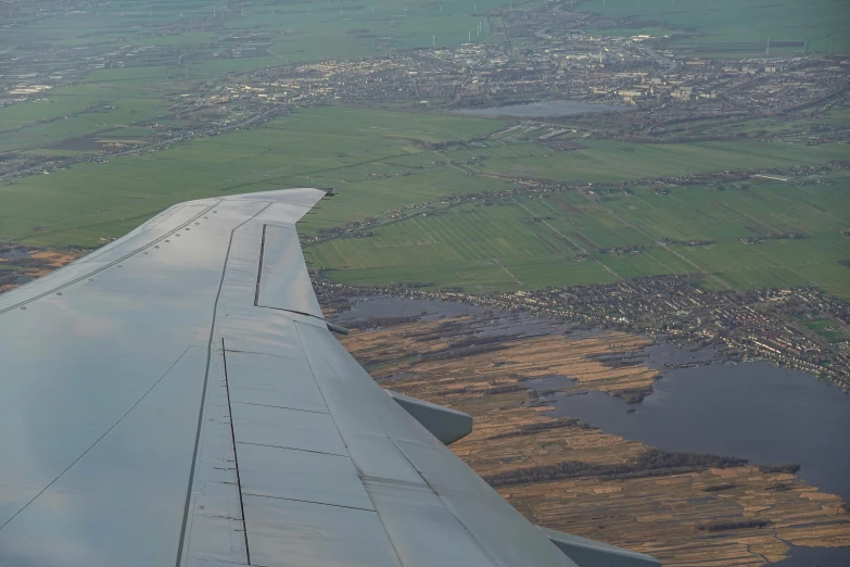 a wing of an airplane flying over the land