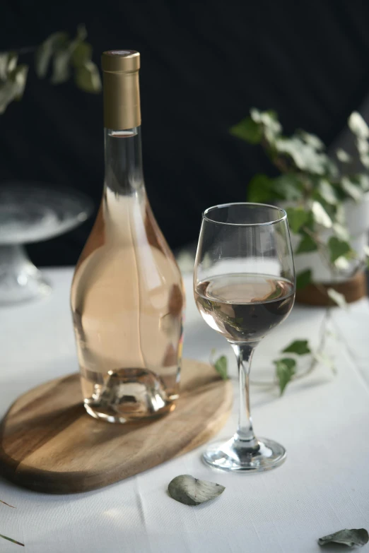 wine glass and bottle sitting on white linen table cloth