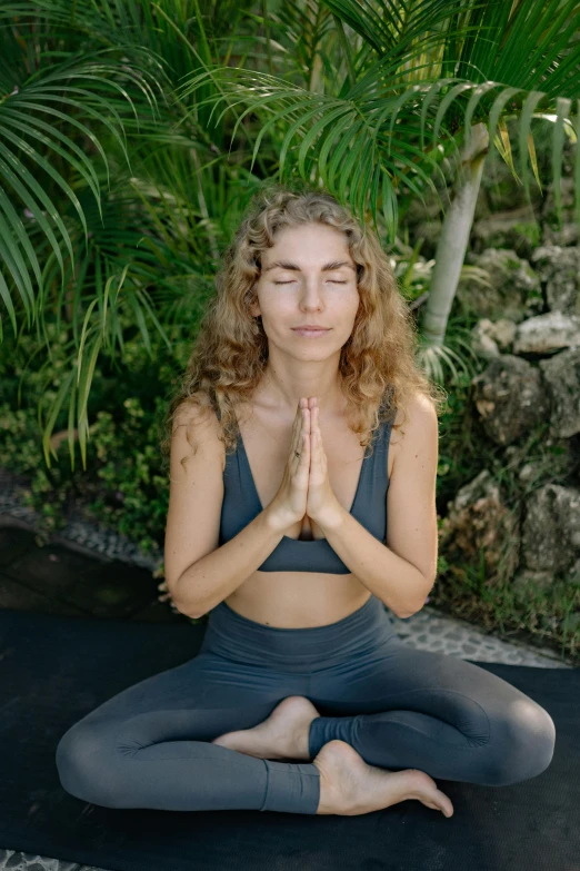 woman sitting in yoga pose with eyes closed on a black mat