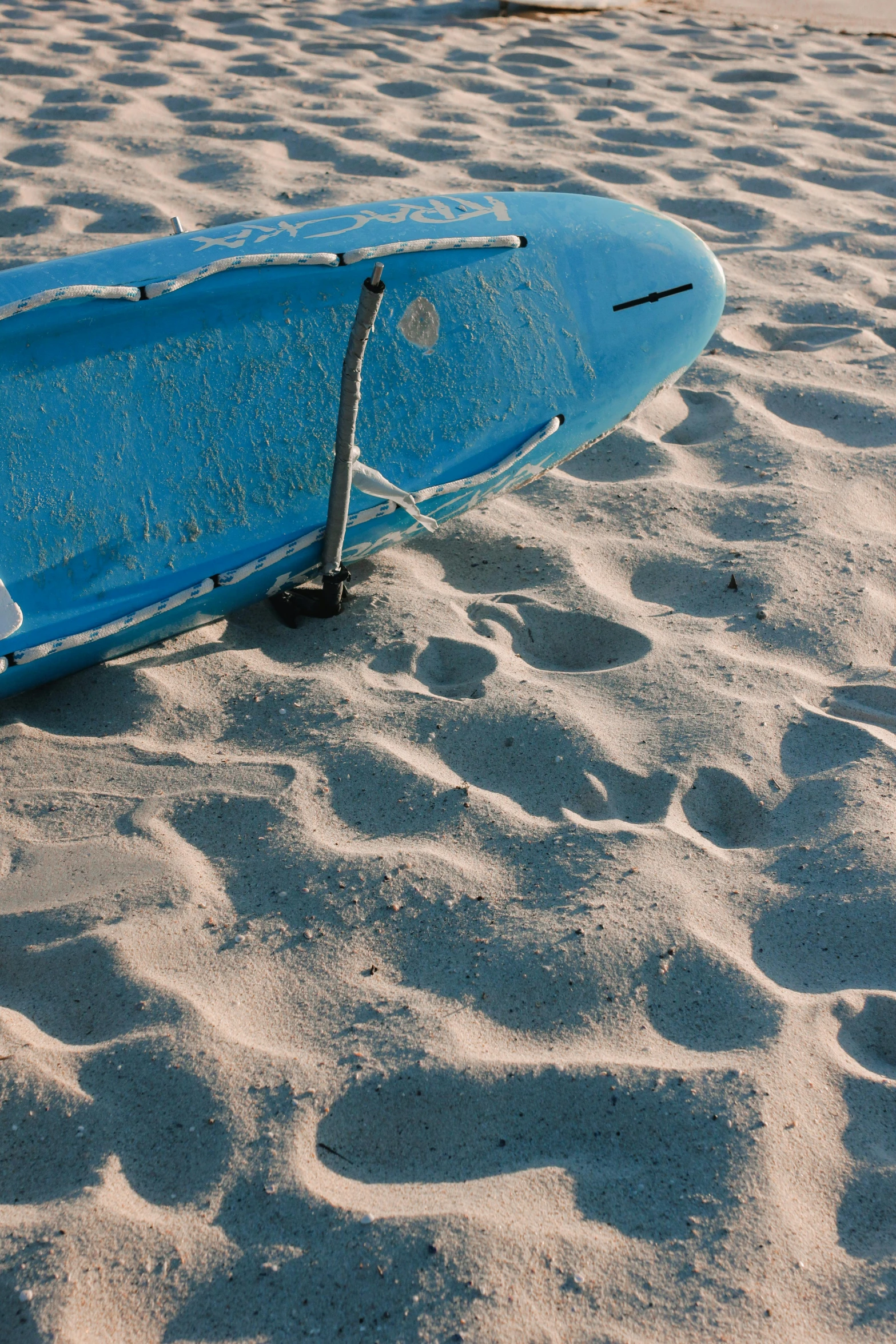 a blue surf board on the sand by itself