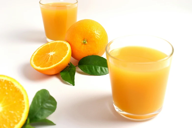 a glass of orange juice with a slice of fruit next to it