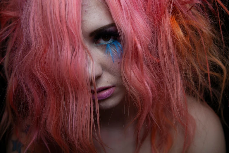 a close up po of a woman with pink hair and blue eye makeup