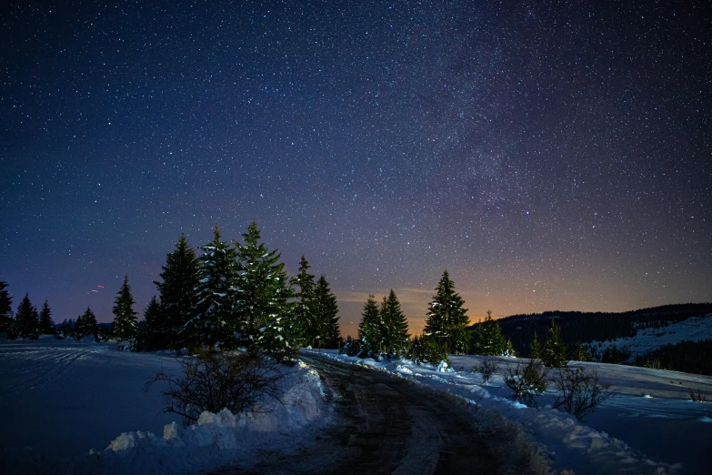 a snowy road under a night sky with stars