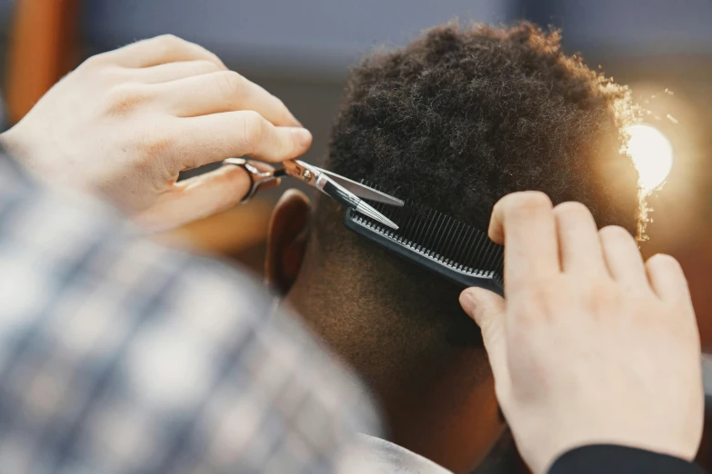 a man is being trim his hair by scissors