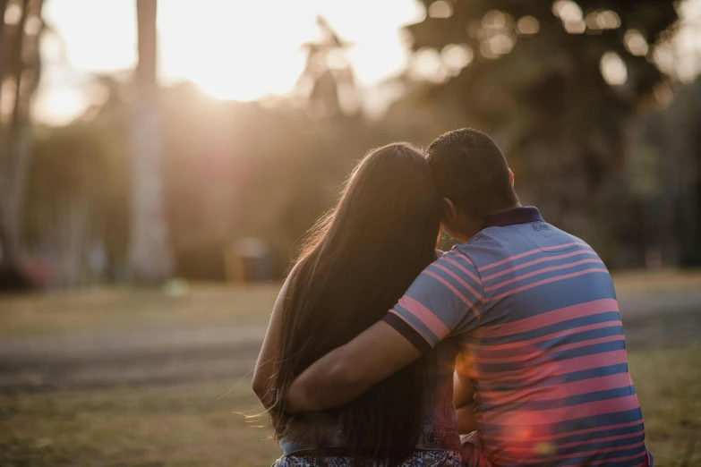 the couple are sitting down and kissing in the field