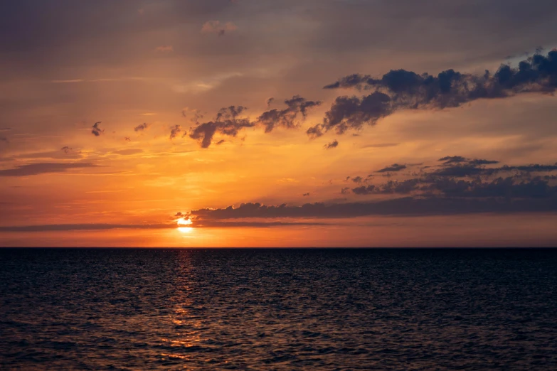 the sun is rising over the ocean as seen from a boat