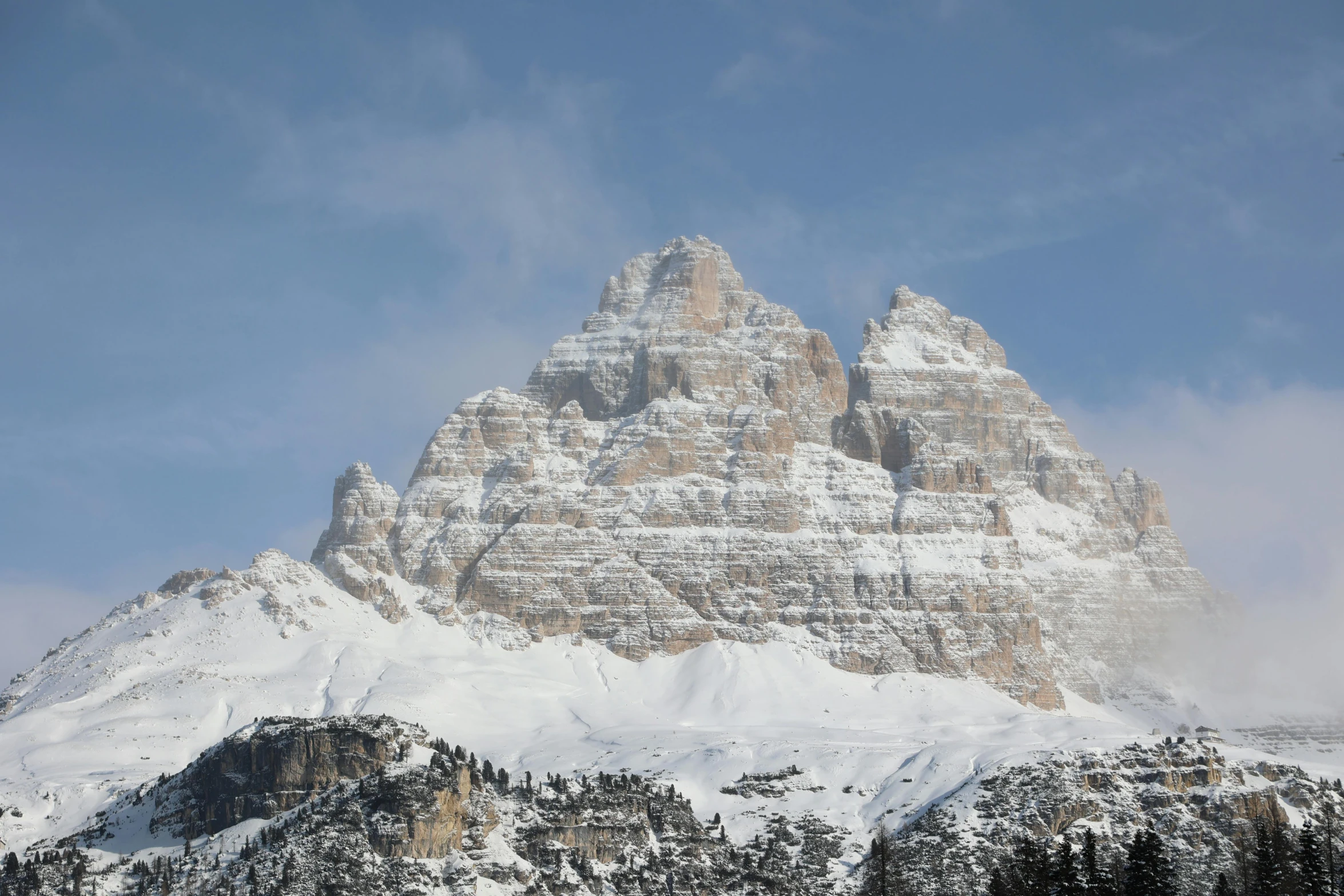 snow covered mountain peaks in front of a partly cloudy sky