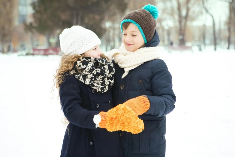 two s standing in the snow with mitts