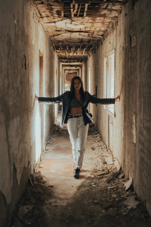 a woman wearing jeans and an open jacket in a rundown building