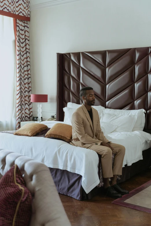 a person sits on a bed with a large headboard