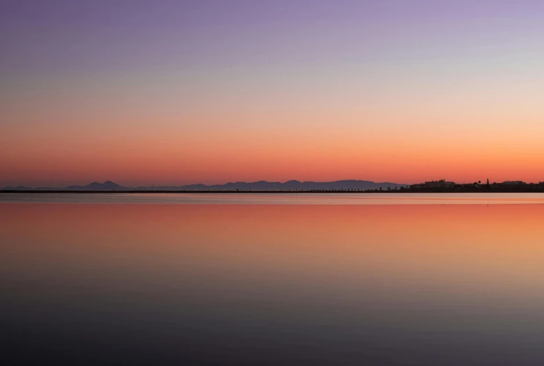 the sun is setting over the mountains and reflecting in water