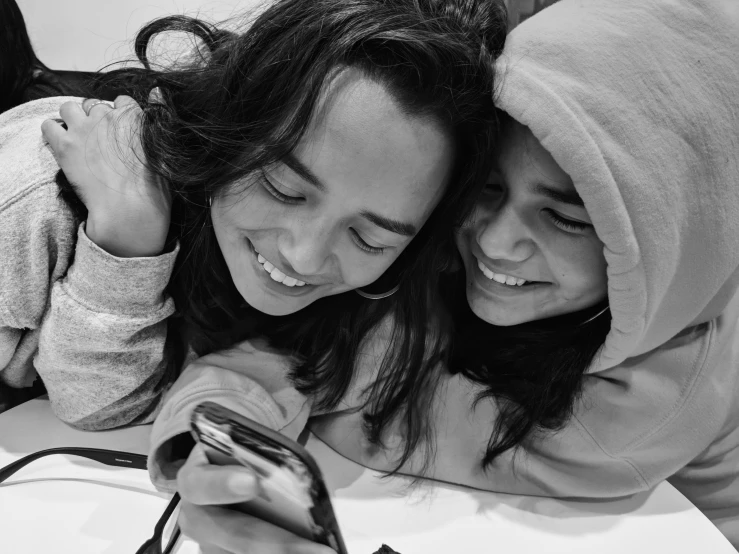 two women are using a cell phone together